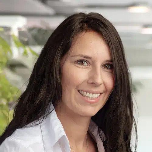 Nahaufnahme von Gabriele Hillenbrand, einer lächelnden Frau mit langen, dunklen Haaren, die ein weißes Hemd trägt. Sie ist Vertriebsberaterin/Customer Service bei Debatin.