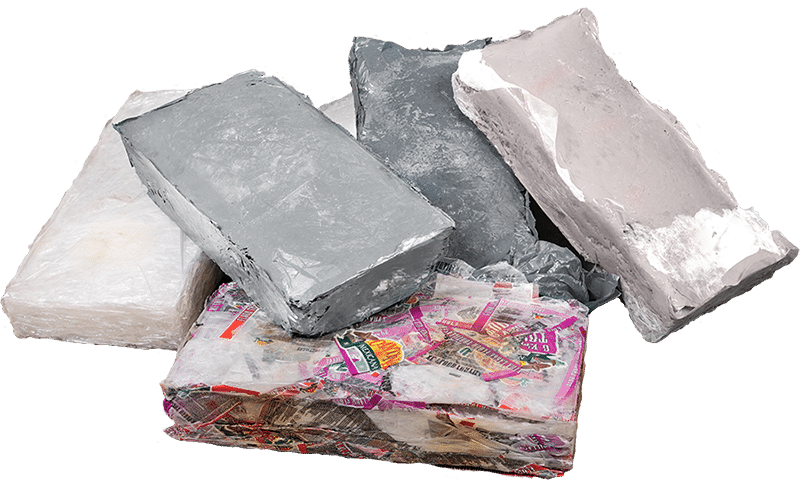 Eine Nahaufnahme mehrerer fester, unregelmäßig geformter Blöcke aus thermisch gepressten und verschmolzenen Kunststofffolien, die die kompakte Form des recycelten Materials nach der Verarbeitung durch eine Thermoballenpresse zeigen.