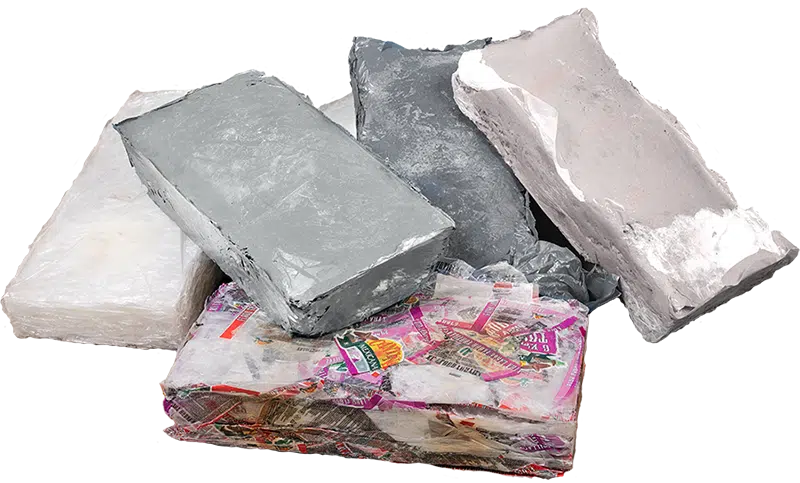 Gepresste Kunstofftaschen Eine Nahaufnahme mehrerer fester, unregelmäßig geformter Blöcke aus thermisch gepressten und verschmolzenen Kunststofffolien, die die kompakte Form des recycelten Materials nach der Verarbeitung durch eine Thermoballenpresse zeigen.