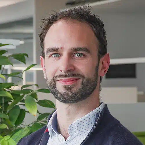 Porträt von Christophe Pille, einem Mann mit dunklem, lockigem Haar und kurzem Bart. Er trägt ein hellblaues Hemd mit Muster und einen dunklen Pullover. Christophe Pille arbeitet im Vertriebsinnendienst bei DEBATIN.