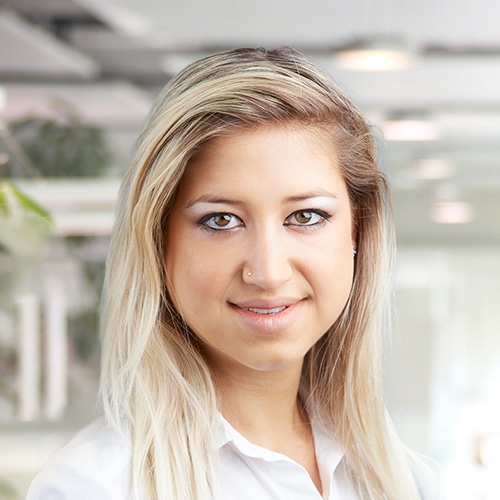 Nahaufnahme von Jennifer Petko, einer freundlichen Mitarbeiterin im Versand / Shipping Department bei Debatin. Ihr offenes Lächeln und die langen, hellblonden Haare fallen auf. Sie trägt eine klassische weiße Bluse, die ihre Professionalität unterstreicht.