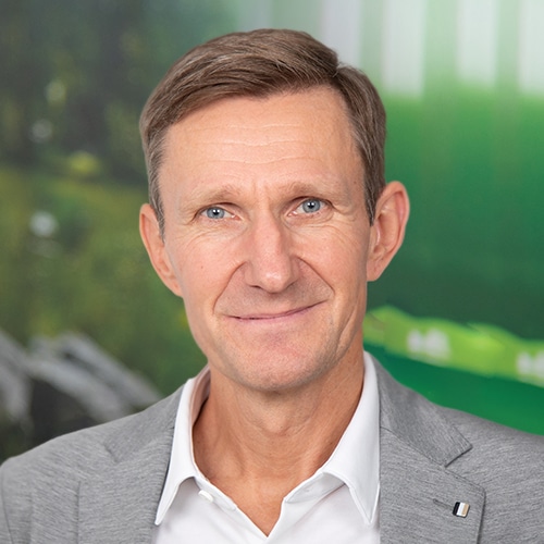 Nahaufnahme von Thomas Rose, dem Geschäftsführer / CEO bei Debatin. Er hat ein offenes, freundliches Lächeln und helle Augen. Er trägt ein weißes Hemd unter einem eleganten grauen Sakko.